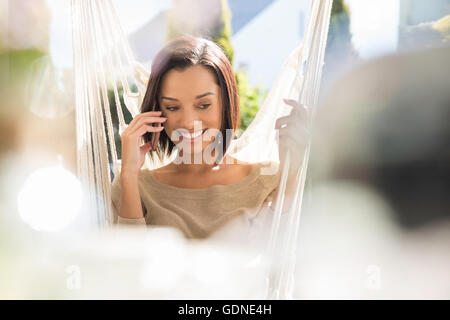 Happy young woman relaxing on garden hammock Stock Photo