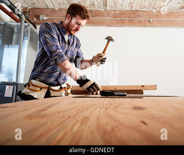 Carpenter in workshop using hammer Stock Photo