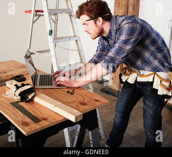 Carpenter in workshop using laptop Stock Photo
