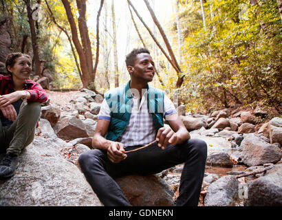 Young male and female hikers sitting on rocks in forest, Arcadia, California, USA Stock Photo