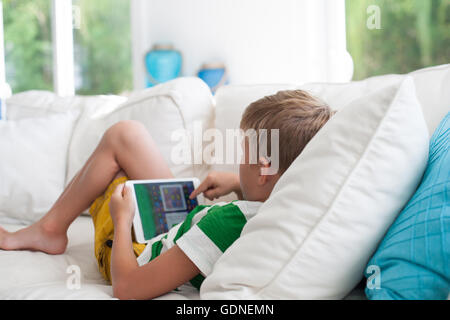 Boy lying on sofa using digital tablet Stock Photo
