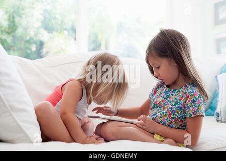 Sisters on sofa using digital tablet Stock Photo