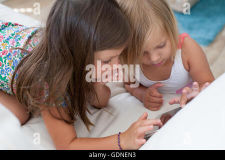 Sisters on sofa using digital tablet Stock Photo