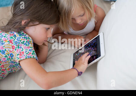 Sisters on sofa using digital tablet Stock Photo