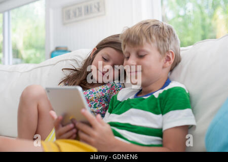 Brother and sister on sofa using digital tablet Stock Photo