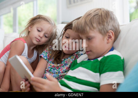 Siblings on sofa using digital tablet Stock Photo