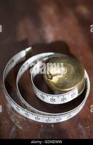 A rolled measuring tape on a dark hardwood surface. Stock Photo