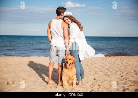 Happy young couple spending time together on the beach with their dog Stock Photo