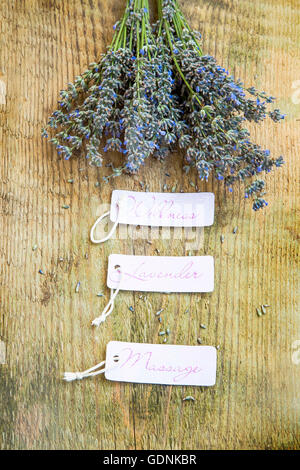 Wellness lavender massage labels with lavender bunch flowers on rustic wooden background Stock Photo