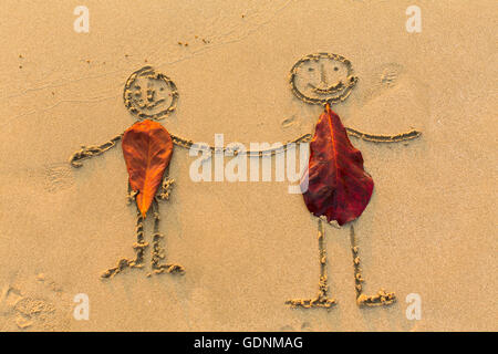 Couple of people figures drawn by hand on the beach sand. Stock Photo