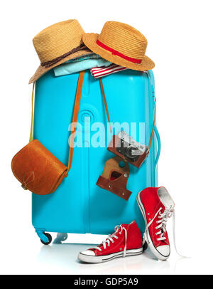 The blue suitcase, sneakers, clothing, hat, and retro camera on white background. Stock Photo