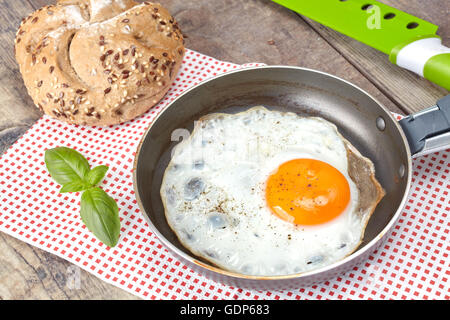 Fried egg in a pan with full grain roll. Stock Photo
