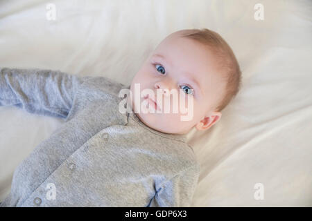 Overhead portrait of blue eyed baby boy lying on bed Stock Photo