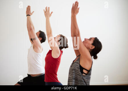 People in exercise studio arms raised in yoga position Stock Photo