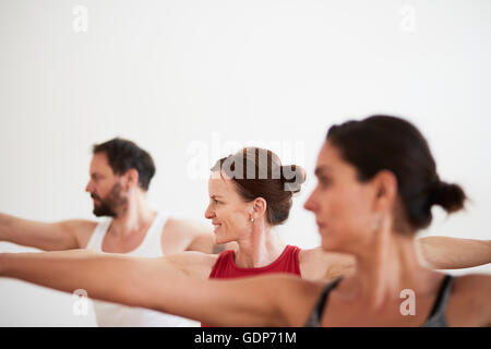 People in exercise studio arms open in yoga position Stock Photo