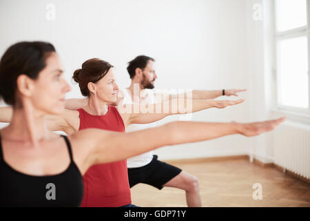 People in exercise studio arms open in yoga position Stock Photo