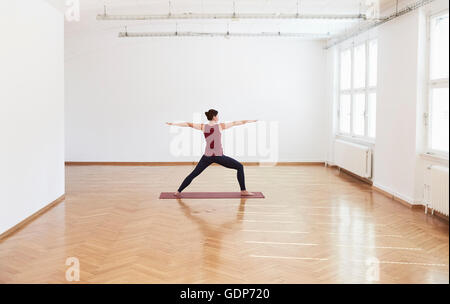 Woman in exercise studio arms open legs apart in yoga position Stock Photo