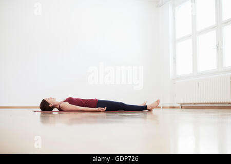 Woman in exercise studio lying on back on floor