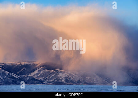 Low storm clouds rolling over snow capped mountains, Baikal Lake, Olkhon Island, Siberia, Russia Stock Photo