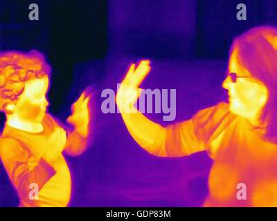 Thermal image of mature woman and son playing hand clapping game Stock Photo