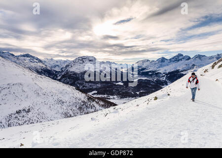 Man walking on snow covered mountain, rear view, Engadine, Switzerland Stock Photo