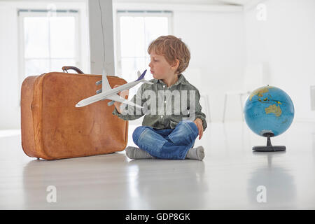 Boy sitting on floor playing with toy airplane Stock Photo