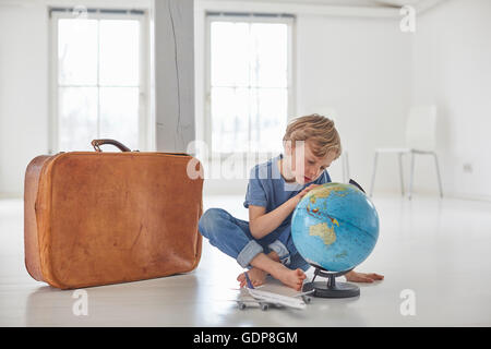 Boy sitting on floor staring at globe Stock Photo