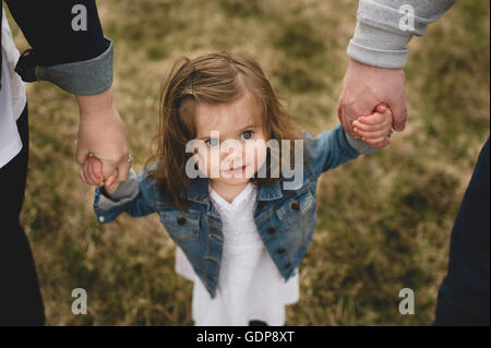 Mother and father holding young daughter's hands, outdoors, elevated view Stock Photo