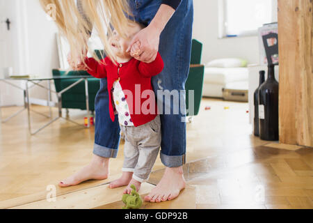 Baby girl holding mothers hands to take first steps Stock Photo