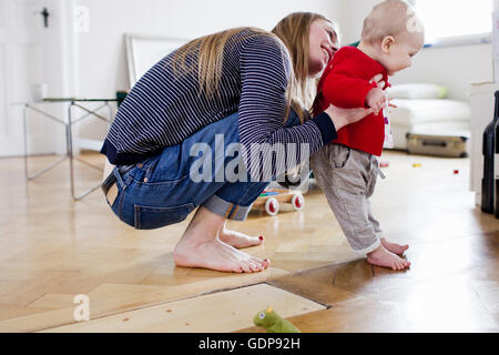 Mid adult woman holding baby daughter to take first steps