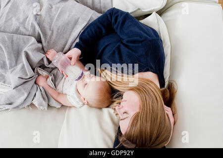 Overhead view of mid adult woman feeding baby daughter on sofa Stock Photo