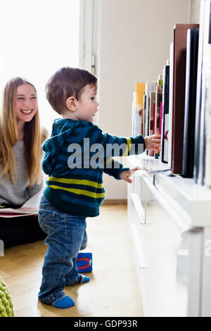 Mid adult woman watching baby son take first steps Stock Photo
