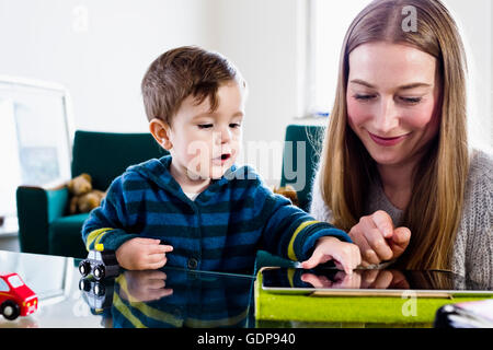 Mid adult woman and baby son using touchscreen on digital tablet at table Stock Photo