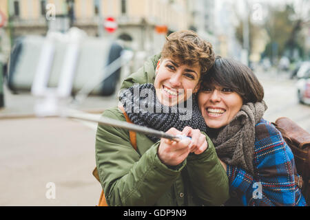 Two sisters, taking self portrait using selfie stick, outdoors Stock Photo