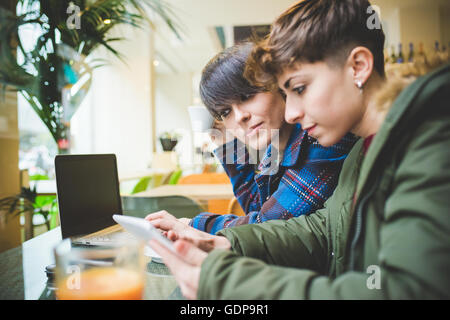 Two sisters in cafe, using digital tablet Stock Photo