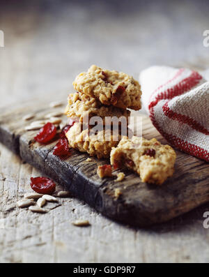 Oat and cranberry cookies, rustic wooden board, vintage tea towel, wooden table Stock Photo