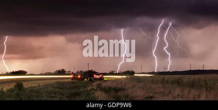 Cloud-to-ground lightning bolts and storm chasers tracking tornadic thunderstorm Stock Photo