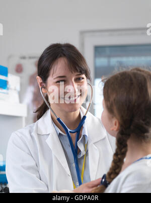 Female paediatric doctor listening to a young girl's chest with a stethoscope in a clinic Stock Photo