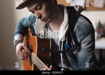 Young man at home, playing guitar Stock Photo