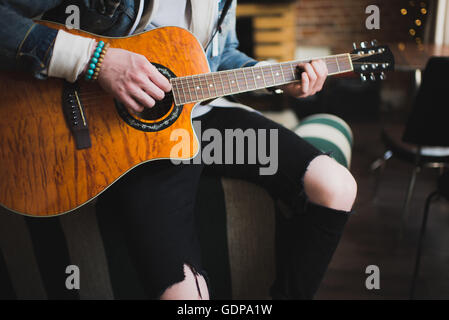 Young man at home, playing guitar, mid section Stock Photo