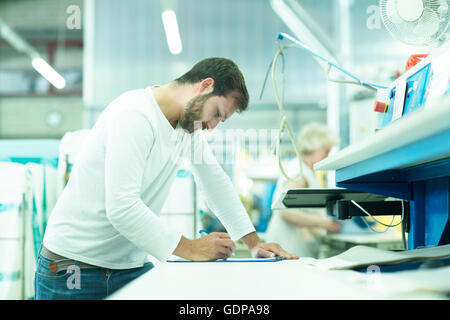 Man working in launderette making notes Stock Photo