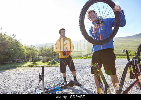 Cyclist attaching bicycle wheel to bicycle Stock Photo