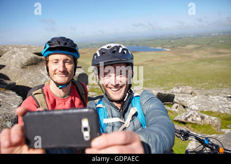 Cyclists with on rocky outcrop taking selfie Stock Photo