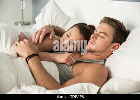 Young couple lying in bed hugging Stock Photo