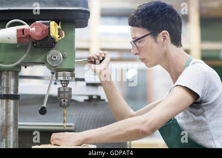 Woman in workshop using drilling machinery Stock Photo