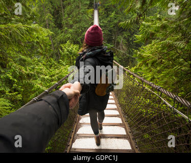 Woman on Lynn canyon suspension bridge holding mans hand, North Vancouver, British Columbia, Canada Stock Photo