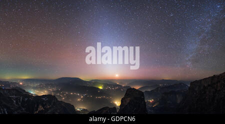 The zodiacal light shines brightly with the Milky Way just after sunset above the lights of towns and villages along the Yangtze Stock Photo