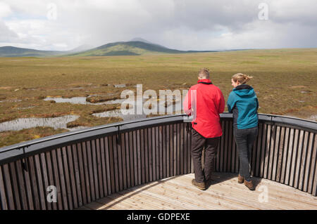 Young couple looking over peatland pools from the viewing tower on the RSPB Dubh Lochan Trail, Forsinard, Sutherland, Scotland. Stock Photo
