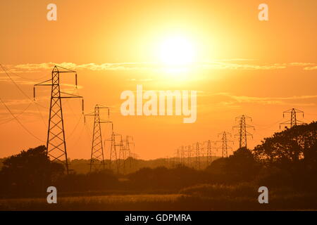 Sun setting behind electricity power lines Stock Photo