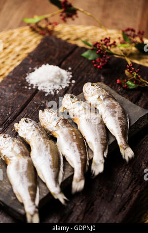Dried Corvina on Rustic Board with Salt and Tree Branches on the Side Stock Photo